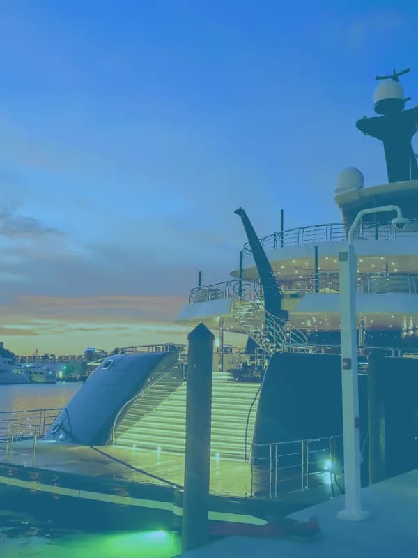 The aft deck of a large yacht at dusk, lit along the stairs