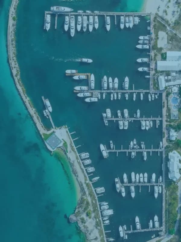 A marina from the air, rows of boats on finger piers beside a narrow strip of land and turquoise shallows